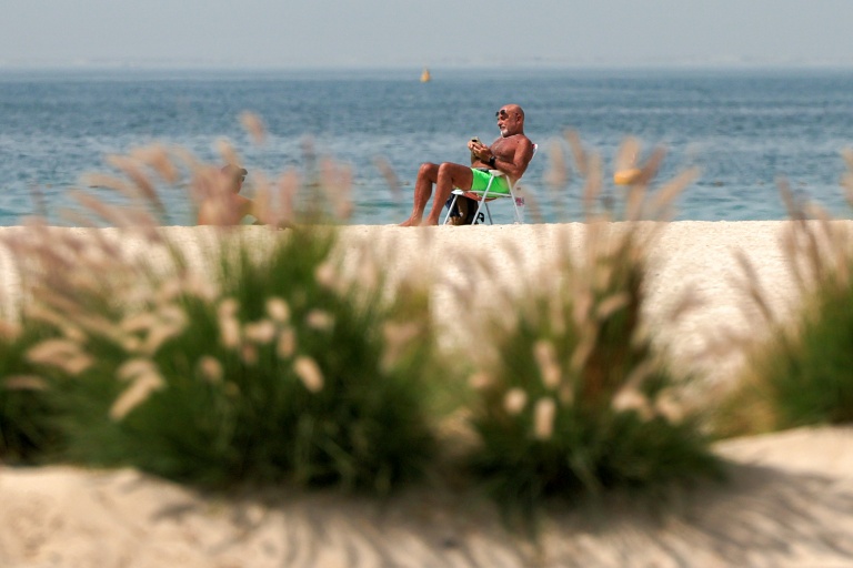 Un homme consulte son téléphone portable sur une plage du quartier de Jumeirah à Dubaï, le 2 mars 202 aux Emirats arabes unis