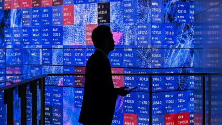 Une personne attend devant un panneau électronique à la Bourse de Tokyo, le 5 novembre 2025