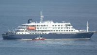Un bateau-ambulance transportant des membres d'équipage en combinaisons de protection  retourne au port de Praia, après une visite à bord du bateau de croisière MV Hondius, au mouillage au large du port, le 5 mai 2026 au Cap-Vert