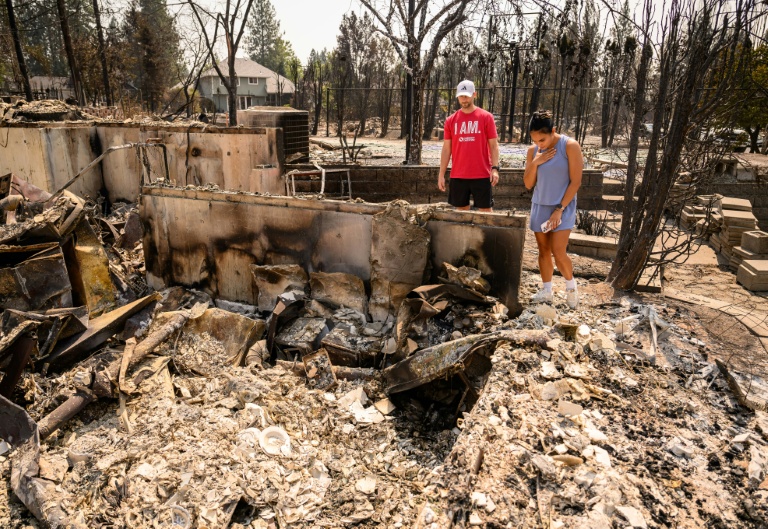 Une femme et son mari tentent de voir si certaines de leurs affaires ont résisté aux flammes, dans les ruines de leur maison réduite en cendres, à Spokane, dans l'Etat de Washington, le 4 août 2026