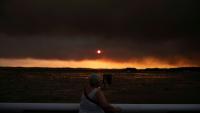 Une femme observe la fumée depuis la plage à Andernos-les-Bains lors d'un incendie dans la forêt de Lège-Cap-Ferret, dans le sud-ouest de la France, le 23 juillet 2026, alors qu'une partie de la zone voisine a été évacuée