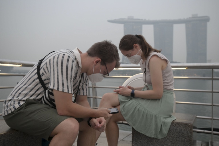 Des touristes portent des masques de protection contre les fumées générées par les incendies indonésiens, le 15 octobre 2026 à Singapour