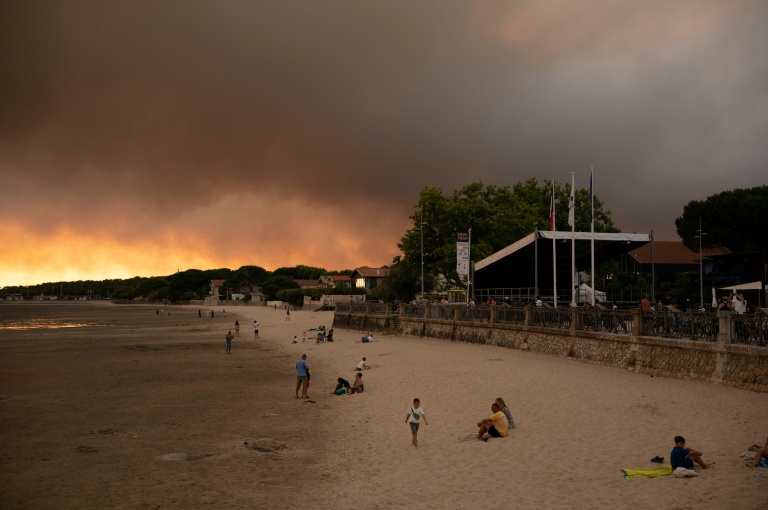 Des touristes sur la plage d'Andernos-Les Bains près de Lège Cap-Ferret où sévit un important incendie, le 23 juillet 2026 