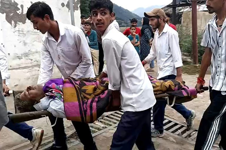 Des hommes transportent un blessé dans une civière à l'hôpital de Kishtwar en Inde le 14 août 2025 après des inondations au Cachemire 