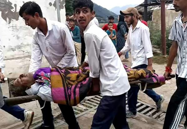 Des hommes transportent un blessé dans une civière à l'hôpital de Kishtwar en Inde le 14 août 2025 après des inondations au Cachemire 