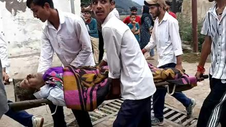 Des hommes transportent un blessé dans une civière à l'hôpital de Kishtwar en Inde le 14 août 2025 après des inondations au Cachemire 