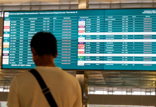 Un passager bloqué à l'aéroport international Soekarno-Hatta en raison de l'éruption du volcan Anak Krakatau, regarde un écran d'information sur les vols, le 7 septembre 2026 à Tangerang, en Indonésie