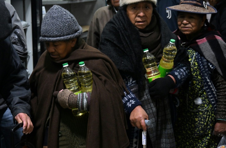 Des habitants repartent avec des bouteilles d'huile achetées dans un magasin Emapa à prix réduit, le 11 juin 2025 à La Paz, en Bolivie