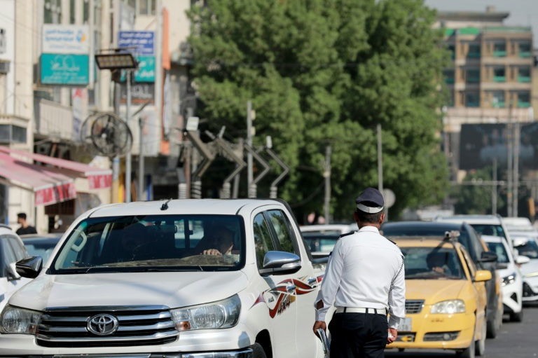 Un policier devant une file d'automobilistes qui attendent devant une station-service à Bagdad, le 5 septembre 2026 en Irak