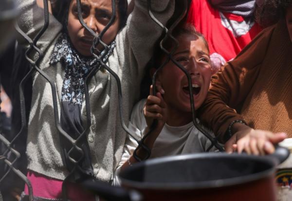 Des enfants palestiniens se bousculent pour obtenir un repas d'une cuisine caritative à Jabalia, dans le nord de la bande de Gaza, le 17 mai 2025
