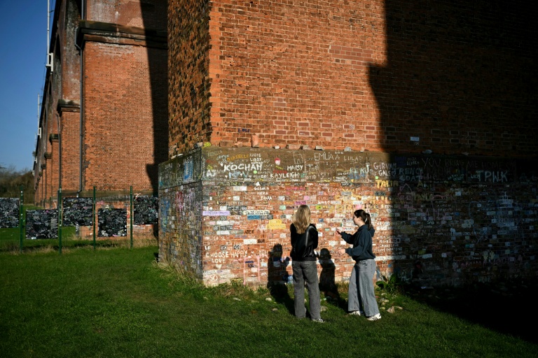 Deux personnnes discutent devant une pile du viaduc de Twemlow, où les fans de Harry Styles viennent écrire des messages, à Holmes Chapel, dans le nord-ouest de l'Angleterre, le 4 mars 2026