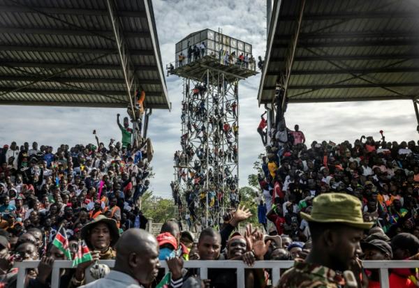 Des partisans de Raila Odinga sont montés sur un château d'eau près du stade où est exposée la dépouille de l'opposant, à Kisumu, dans l'ouest du Kenya, le 18 octobre  2025