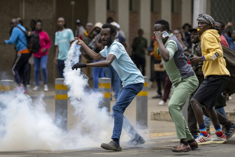 Un manifestant kényan renvoie une grenade lacrymogène vers la police anti-émeute, à Nairobi, le 12 juin 2025