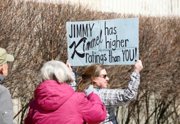 Une personne brandit une pancarte sur laquelle est écrit "Jimmy Kimmel a de meilleures audiences que toi" à Chicago lors d'une journée nationale de protestation contre le président américain Donald Trump, le 28 mars 2026