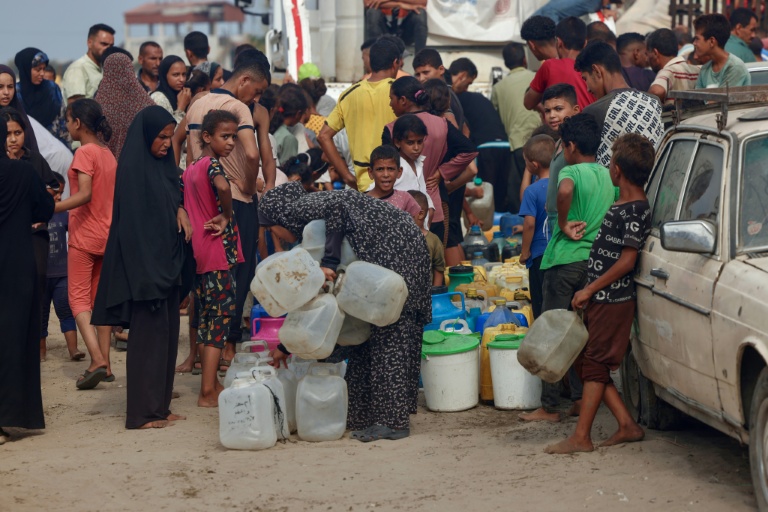 Des Palestiniens font la queue pour remplir des bidons d'eau, à al-Mawasi, dans le sud de la bande de Gaza, le 12 août 2025
