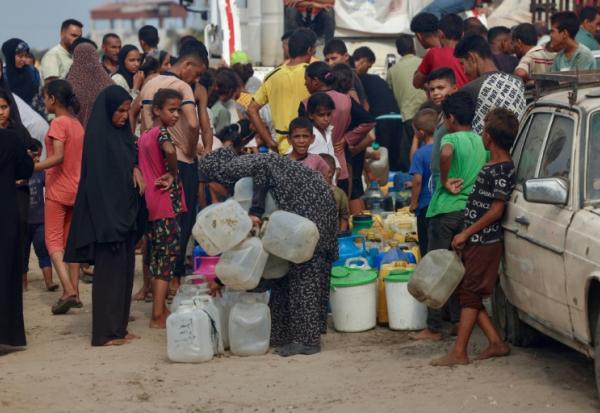 Des Palestiniens font la queue pour remplir des bidons d'eau, à al-Mawasi, dans le sud de la bande de Gaza, le 12 août 2025