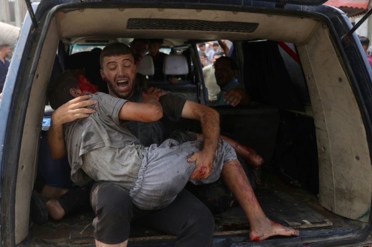 Un homme évacue un jeune blessé après une frappe israélienne à Gaza-ville, le 12 août 2025