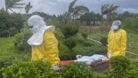 Des membres du personnel soignant en combinaison de protection transportent un patient à Rwampara après qu'un hôpital a été incendié par des manifestants qui s'étaient vu refuser l'accès aux corps de leurs proches décédés du virus Ebola, le 21 mai 2026 en RDC