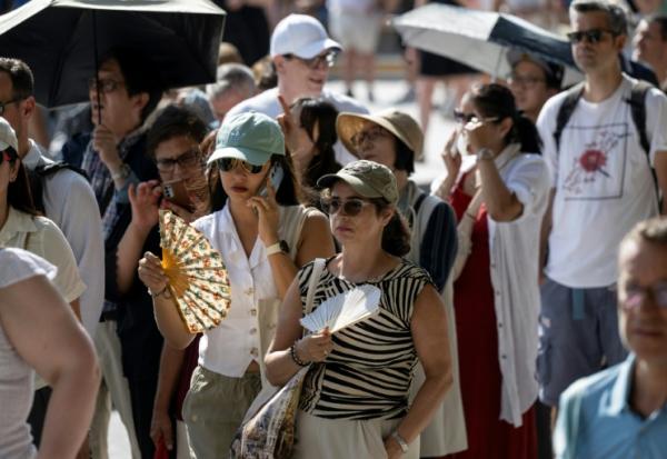 Des touristes avec des éventails devant la cathédrale Notre-Dame, le 16 août 2025 à Paris