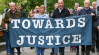 Des proches des victimes du "Bloody Sunday" brandissent une banderole sur laquelle est écrit "Towards Justice" (En faveur de la justice) alors qu'ils se rendent à pied au tribunal de Belfast, en Irlande du Nord, le 16 octobre 2025