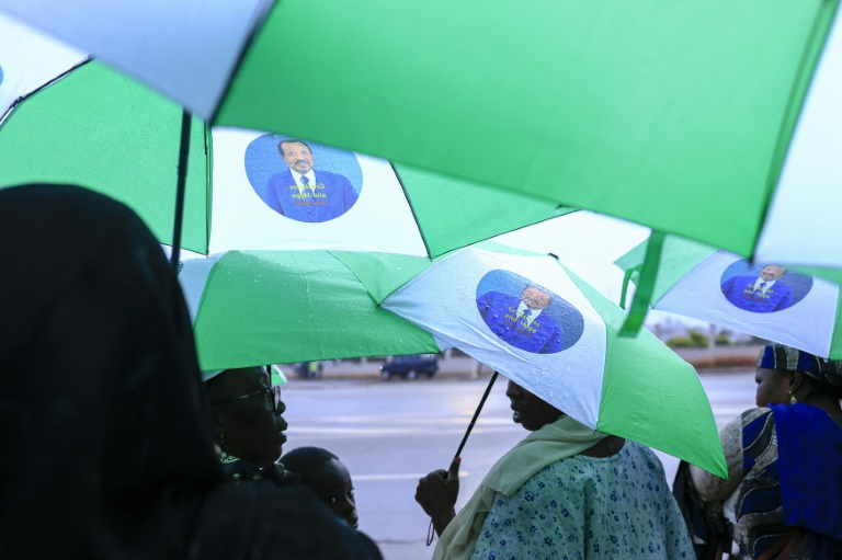Des militants s'abritent sous des parapluies à l'effigie du président camerounais sortant et candidat Paul Biya, à Yaoundé, le 1er octobre 2025, à l'approche de l'élection présidentielle prévue le 12 octobre 2025