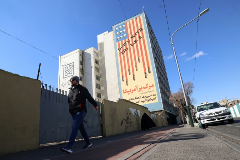 Un Iranien passe devant une immense fresque anti-américaine peinte sur un bâtiment dans la capitale iranienne, Téhéran, le 31 janvier 2026