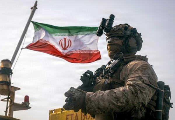 Cette photographie fournie par le Corps des Marines des États-Unis, prise le 16 juillet 2026 par le service des relations publiques du Commandement central américain, montrerait un drapeau iranien flottant derrière un marine américain de la 11e Unité expéditionnaire des Marines, dans le Golfe.