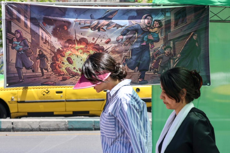 Une Iranienne passe devant une banderole représentant l'attaque américano-israélienne contre l'Iran, dans la capitale Téhéran, le 9 mai 2026