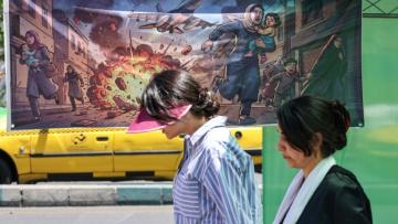 Une Iranienne passe devant une banderole représentant l'attaque américano-israélienne contre l'Iran, dans la capitale Téhéran, le 9 mai 2026