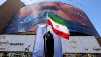 Une Iranienne brandit le drapeau de son pays, devant une panneau représentant le président américain Donald Trump, à Téhéran le 10 mai 2026