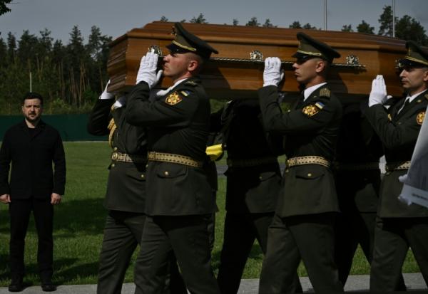 Le président ukrainien Volodymyr Zelensky (g) participe à la cérémonie de réinhumation du leader nationaliste controversé Andriï Melnyk, décédé en 1964 et ancien chef d'une branche de l'Organisation des nationalistes ukrainiens (OUN), ainsi que de son épouse Sofia, au cimetière national militaire commémoratif près de Kiev, le 25 mai 2026