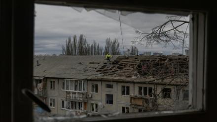 Des ouvriers dégagent les débris du toit d'un immeuble résidentiel fortement endommagé après une frappe de drone russe à Kyiv, le 23 décembre 2025 en Ukraine