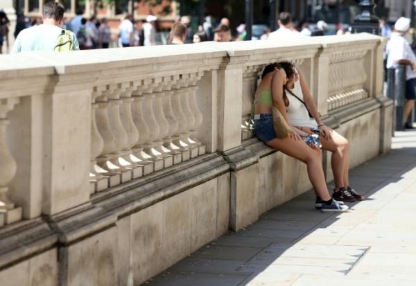 Des personnes se protégent du soleil derrière un mur, le 24 juin 2026 à Londres