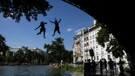 Des jeunes sautent d'un pont dans le canal Saint-Martin lors d'une vague de chaleur à Paris, le 22 juin 2026