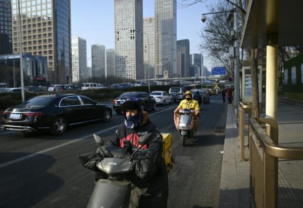 Des livreurs de repas conduisent des scooters électriques à Pékin, le 16 janvier 2024