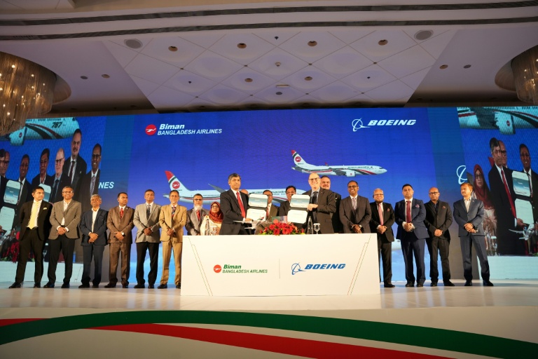 Photo diffusée par Biman Bangladesh Airlines montrant le PDG de compagnie aérienne, Kaizer Sohel Ahmed (g), et le vice-président de Boeing, Paul Righi (d), échangeant des documents après la signature d'un accord à Dacca, le 30 avril 2026 au Bangladesh