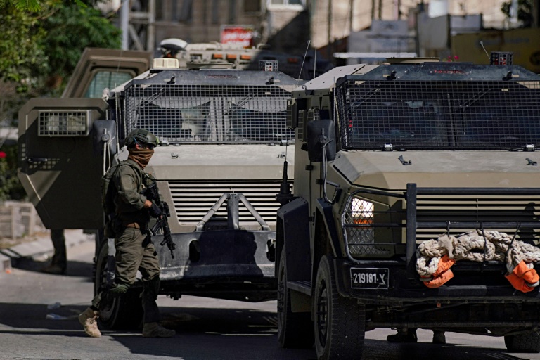 Des soldats israéliens à côté de véhicules blindés lors d'un raid militaire à Jénine, le 21 mai 2025 en Cisjordanie occupée