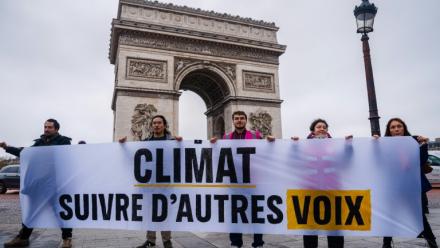 Des militants tiennent une banderole "Climat, écoutez les autres voix" lors d'une action de Greenpeace devant l'Arc de Triomphe à Paris, le 12 décembre 2025, à l'occasion du 10e anniversaire de la signature des accords de Paris sur le climat