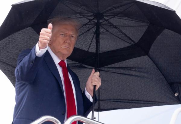 Le président américain Donald Trump tient un parapluie et lève le pouce alors qu'il monte à bord d'Air Force One avant son départ de la base aérienne d'Andrews, près de Washington, le 12 octobre 2025