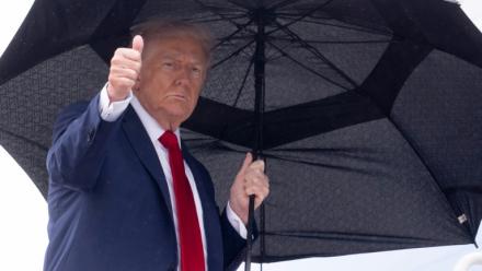 Le président américain Donald Trump tient un parapluie et lève le pouce alors qu'il monte à bord d'Air Force One avant son départ de la base aérienne d'Andrews, près de Washington, le 12 octobre 2025