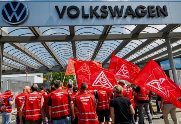 Des salariés de Volkswaggen, portant des drapeaux d'IG Metall, protestant contre le plan de restructuration préparé par la direction, à Zwickau, le 9 juillet 2026