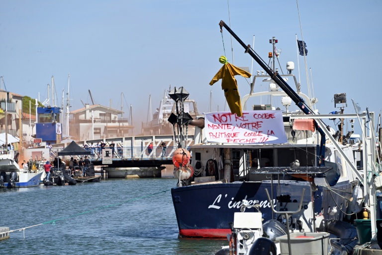 Une effigie suspendue à une grue, à côté d'une banderole, sur un bateau au port du Grau-du-Roi, lors d'une manifestation de pêcheurs contre la flambée des prix du carburant, le 17 septembre 2026 dans le Gard