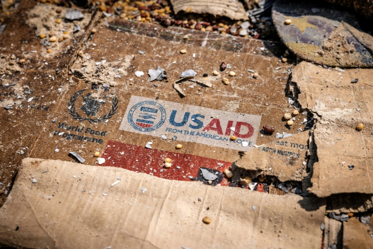 Un logo de l'Usaid sur un carton au milieu de restes éparpillés de boîtes et de matériaux abandonnés après des actes de vandalisme et de pillages à l'entrepôt du Programme alimentaire mondial (PAM) à Bukavu, le 21 février 2025 en RDC