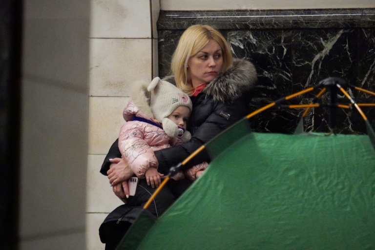 Une femme tient un enfant dans ses bras alors que des personnes se réfugient dans une station de métro pendant une attaque aérienne russe, à Kiev, tôt le matin du 3 février 2026, dans le contexte de l'invasion russe de l'Ukraine.