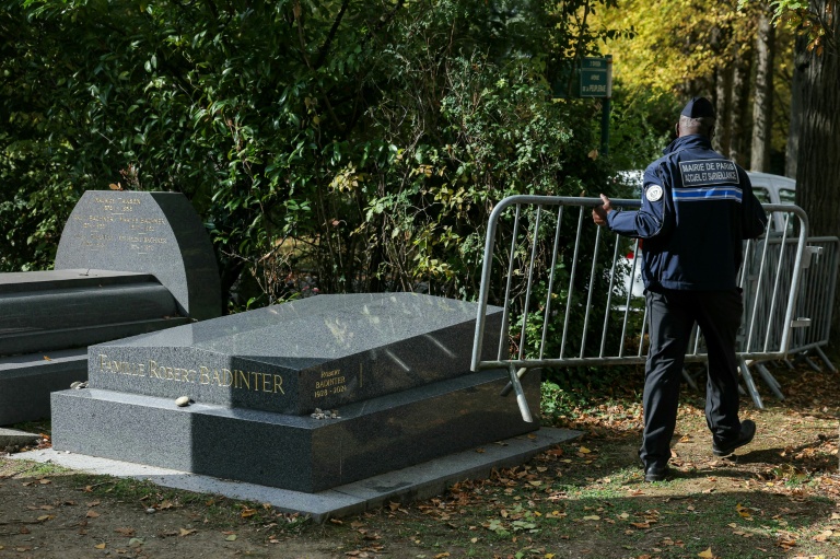 Un policier enlève le 9 octobre 2025 au cimetière de Bagneux, près de Paris, les barrières qui protégeaient la tombe de Robert Badinter, nettoyée après avoir été profanée à quelques heures de son entrée au Panthéon