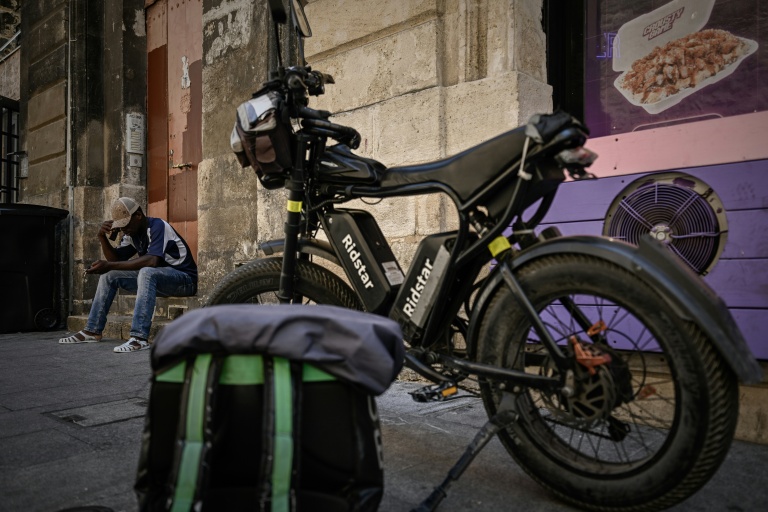 Un livreur à vélo attend des commandes devant un restaurant à Bordeaux, le 7 juillet 2026 lors d'une vague de chaleur en France