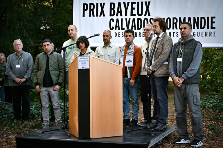 (g-d) Le journaliste de guerre américain Jon Lee Anderson, les collaborateurs de l'AFP Belal Al-Sabbagh, Mohannad Shahwan, Mai Yaghi, Adel Zaanoun, Said Khatib, Mohammed Abed, le directeur général de RSF Thibault Bruttin et le collaborateur de l'AFP Mahmud Hams rendent hommage aux journalistes morts à la guerre devant le mémorial 2024-2025 en hommage aux journalistes décédés au cours de l'année écoulée, à l'occasion du 