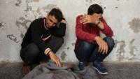 Des Palestiniens pleurent près d'un corps enveloppé dans une couverture à l'hôpital Al-Ahli, le 7 mai 2025, après une frappe israélienne dans la ville de Gaza