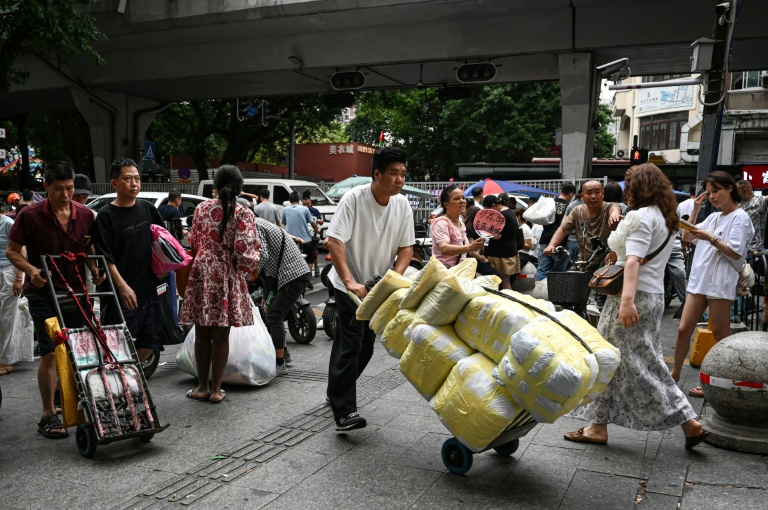 Un homme transportant des ballots de vêtements vers un marché de gros de Canton, en Chine, le 16 avril 2026
