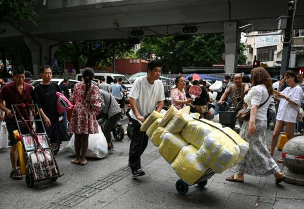 Un homme transportant des ballots de vêtements vers un marché de gros de Canton, en Chine, le 16 avril 2026